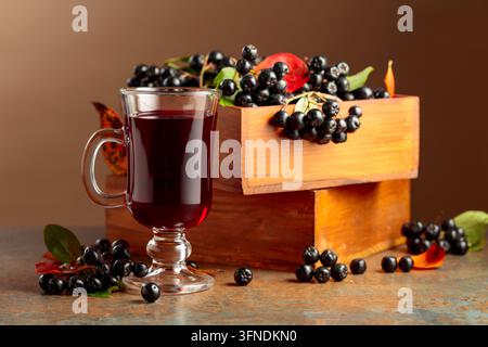 Glas Aroniabeer und frische Beeren in einer Holzkiste. Stockfoto
