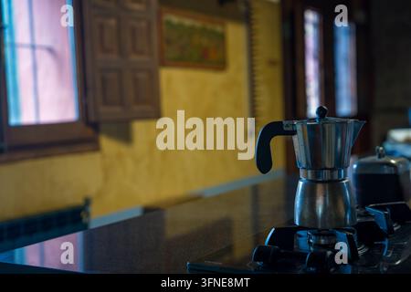 Moka Pot Kaffeezubereitung auf einem Herd in einer warmen Kücheneinrichtung. Stockfoto