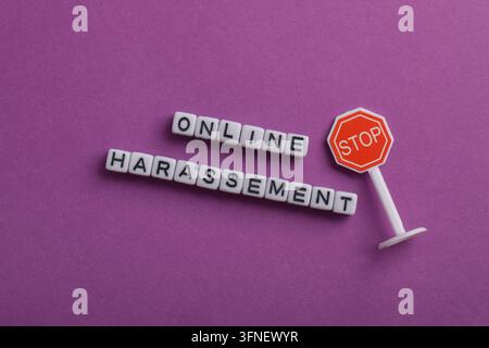 Stopp Online-Belästigung Konzept mit Buchstabenperlen und einem Stoppschild auf lila Hintergrund, repräsentierend Cybermobbing-Prävention, digitale Sicherheit, Respekt Stockfoto