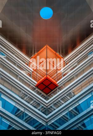 Architektonisches Detail mit geometrischen Formen, einer symmetrischen und minimalistischen Komposition, Reflexionen auf dem Glas und einer Öffnung in der Decke. Stockfoto