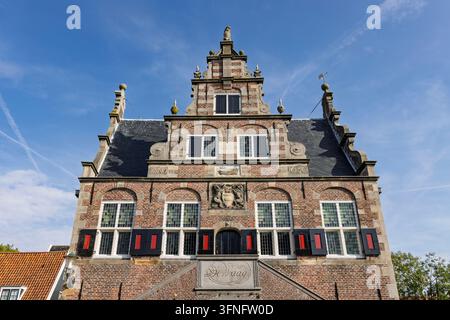 De Rijp, Niederlande. Nahaufnahme der kunstvollen Ziegelfassade, der schönen Stufengiebel und der detaillierten Steinkreuze des historischen Waaghauses (De Waag) Stockfoto
