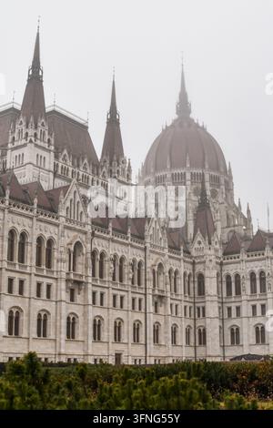 Ungarisches Parlamentsgebäude in Budapest, Ungarn, mit seinen neogotischen Türmen und der zentralen Kuppel, die in dichten Winternebel verschwinden. Stockfoto