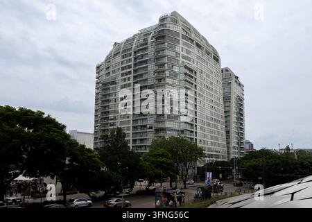 Mexiko-Stadt, Mexiko - 23. August 2026: Weite urbane Ansicht eines hohen modernen Wohngebäudes mit geschwungenen Glasbalkonen, das über grüne Bäume in Nue aufragt Stockfoto