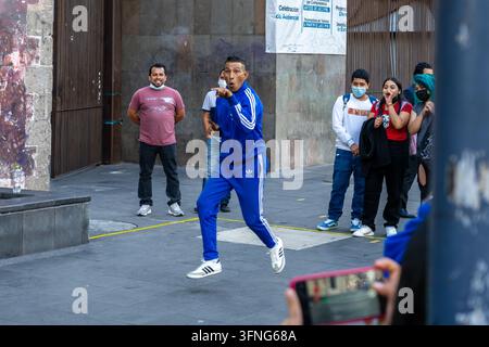 Mexico-Stadt Mexiko - 18. Februar 2022: Ein Breakdancer in Mexico-Stadt zeigt auf die Menge und springt, während Passanten und Touristen zuschauen Stockfoto