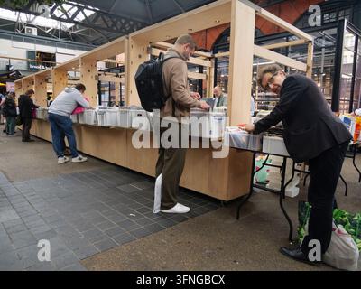 Einkäufer durchstöbern und sortieren Kisten mit klassischen Vinylplatten und CDs an einem Musikstand im historischen Old Spitalfields Market im East End von London, UK Stockfoto
