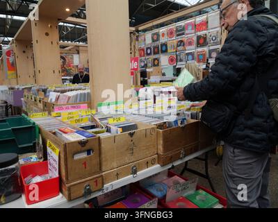 Einkäufer durchstöbern und sortieren Kisten mit klassischen Vinylplatten und CDs an einem Musikstand im historischen Old Spitalfields Market im East End von London, UK Stockfoto