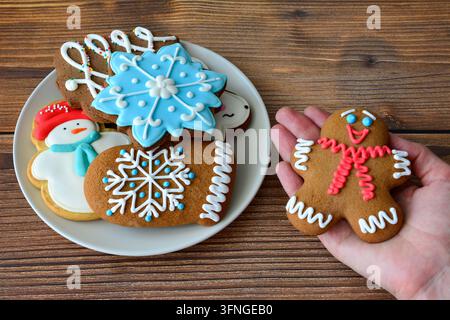Hand hält einen Lebkuchenmann mit Weihnachtskeksen auf einem Teller Stockfoto