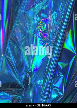 Gefältertes irisierendes Material reflektiert lebhafte blaue, grüne und violette Farbtöne und erzeugt eine schimmernde, metallische Textur. Studioaufnahme eines abstrakten Hintergrunds Stockfoto