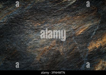 Detaillierte dunkle strukturierte Oberfläche mit grauen, schwarzen und goldbraunen mineralartigen Mustern, geeignet als abstrakter Hintergrund oder im Naturstein-Stil für Text Stockfoto