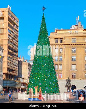 SANTIAGO, CHILE - 03. DEZEMBER 2025: Ein hoher geschmückter Weihnachtsbaum steht auf dem Plaza de Armas-Platz, umgeben von historischen Gebäuden und Palmen in San Stockfoto