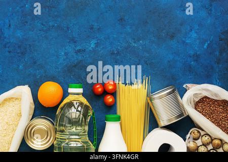 Lieferung von Lebensmitteln nach Hause. Notwendige Produkte während einer Pandemie und Quarantäne auf blauem rustikalem Hintergrund. Spende und Wohltätigkeit. Oberansicht, Flat Lay, Kopierraum. Stockfoto