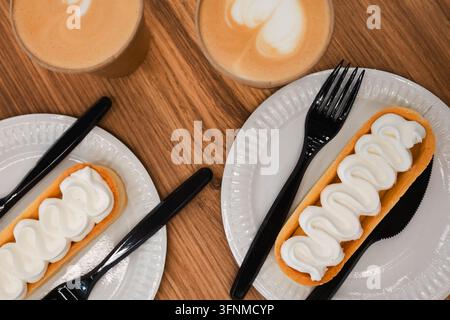 Zitronenkuchen mit Schlagsahne und zwei Kaffeetassen. Zitronenkäsekuchen und Kaffeetassen. Kaffeepause für zwei. Cappuccino und Dessert. Zitronentarte Stockfoto