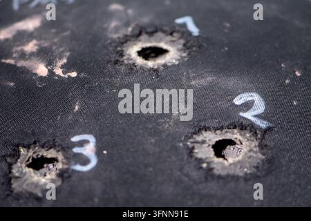 WIEN, ÖSTERREICH, 26. Oktober 2025: Nahaufnahme von drei Einschusslöchern, die durch eine nummerierte schwarze Stoffscheibe geschlagen wurden. Stockfoto