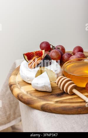 Vorspeisenbrett mit Fleisch, Käse, Trauben, Nüssen, Honig und frischen Feigen. Charcuterie-Teller auf einer beigen Leinentischdecke. Stockfoto