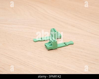 Grüne elektrische Klemmblöcke auf Holz - Zwei grüne Kunststoff-Elektro-Klemmblöcke mit Schraubverbindern sind ordentlich auf einem hellen Holzba... Stockfoto