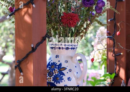 Eine blau-weiße Blumentasse hält einen kleinen Strauß Gartenblumen im Freien. Stockfoto