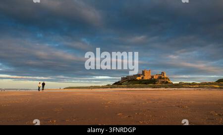 Paar spaziert am Strand nahe Bamburgh Castle an der Küste von Northumberland. Stockfoto