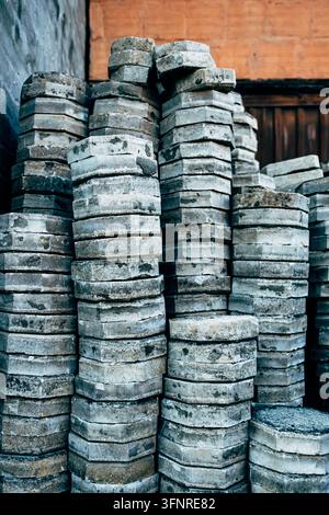 Gestapelte Betonpflastersteine, die auf einem Baustellengelände aufgeschichtet sind, graue sechseckige Pflastersteine in unebenen Türmen, Baumaterial-Hintergrund, selektive Fokussierung. Stockfoto