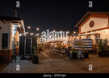 Freiluftrestaurant unter dekorativen Lichtern zwischen historischen Hallen auf dem Markt in Holešovice in Prag. Prag, Tschechische Republik, 4. Oktober 2026. Stockfoto
