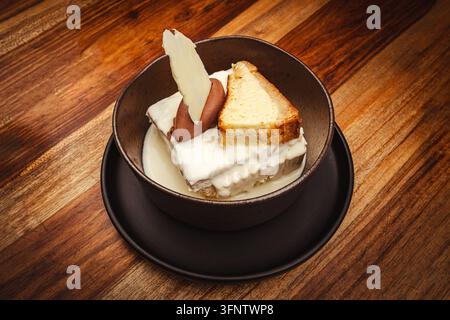 Gourmet-Dessert serviert in einer Schüssel mit einer Kuchenstück, Sahne und Schokoladendekor Stockfoto