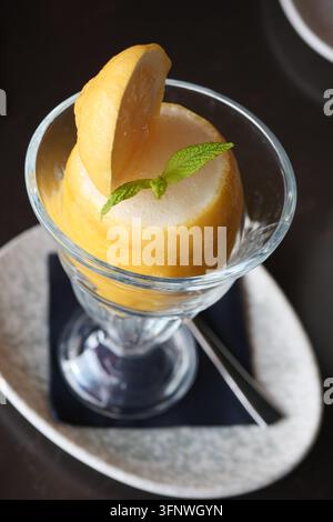 Zitronensorbet in einem Glas serviert mit einer Scheibe und einem Minzblatt oben Stockfoto