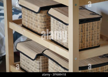 Holzregale in einem minimalistischen Raum sind mit verschiedenen Aufbewahrungsboxen bestückt Stockfoto