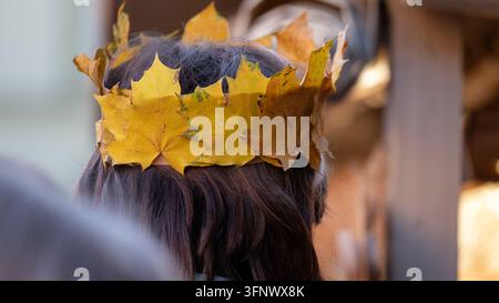 Handgefertigte Herbstlaubkrone aus bunten natürlichen Blättern, getragen als saisonales Kopfschmuckstück, illustriert Herbsthandwerk, naturinspirierte Mode, Kreativität Stockfoto