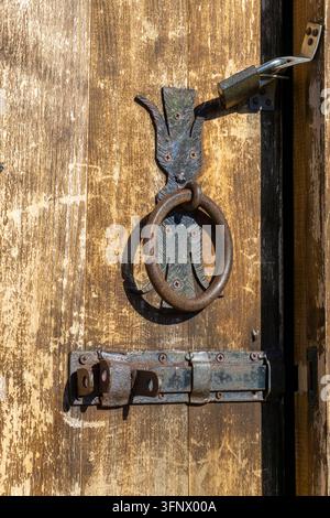 Rostiger Klopfer und Bolzen an einer alten Holztür. Alte Farbe und Holzstruktur sind sichtbar. Georgia. Stockfoto