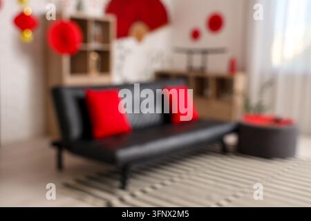 Verschwommener Blick auf das moderne Wohnzimmer mit schwarzem Sofa und Dekoration für das chinesische Neujahrsfest Stockfoto