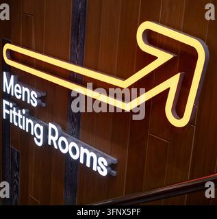 Beleuchteter Neonpfeil und Herren-Umkleide-Schild montiert an einer Holzwand Stockfoto