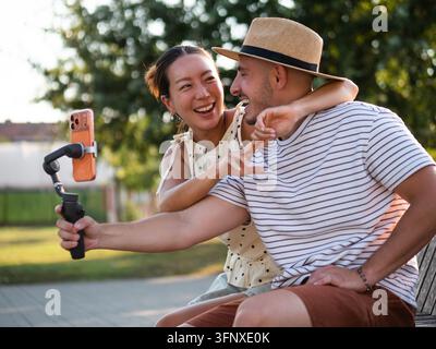 Junger Mann und Frau teilen einen verspielten Moment, während sie Inhalte für soziale Medien erstellen. Stockfoto