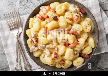 cremige Gnocchi Carbonara mit einer reichhaltigen herzhaften Sauce aus Eiern, Käse und Pancetta, Nahaufnahme auf dem Teller auf dem Tisch. Horizontale Ansicht von oben Stockfoto