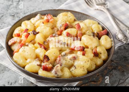 cremige Gnocchi Carbonara mit einer reichhaltigen herzhaften Sauce aus Eiern, Käse und Pancetta, Nahaufnahme auf dem Teller auf dem Tisch. Horizontal Stockfoto
