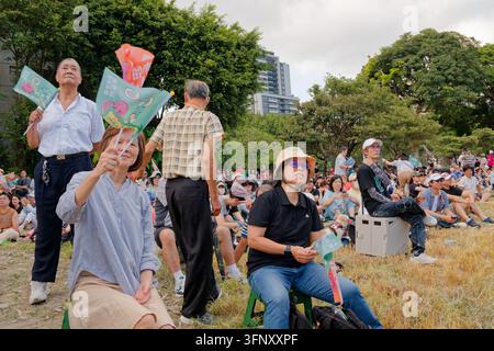 Taipei, Taiwan - 04. Okt. 2026: Unterstützer schwenken Fahnen auf einem Rasen am Eröffnungskundgebungshauptquartier des Kandidaten für das Amt des Bürgermeisters der DPP, Puma Shen, während die Menge sitzt. Stockfoto