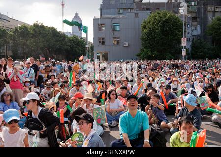 Taipeh, Taiwan - 04. Okt. 2026: Anhänger sitzen auf der Straße und blicken auf eine Großbildübertragung bei der Eröffnung der Puma Shen-Kampagnen-Zentrale. Stockfoto