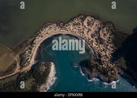 Luftaufnahme von Voidokilia Beach mit seiner ikonischen bogenförmigen Küstenlinie, türkisfarbenem Wasser und den umliegenden Sanddünen in Griechenland. Stockfoto