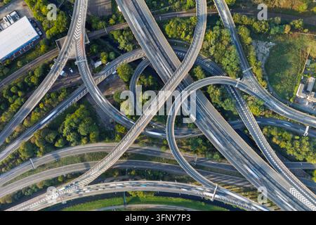 Luftbild einer komplexen Autobahnkreuzung mit mehreren sich kreuzenden Straßen und weiten Kurven, umgeben von üppigen grünen Bäumen und Vegetation in th Stockfoto