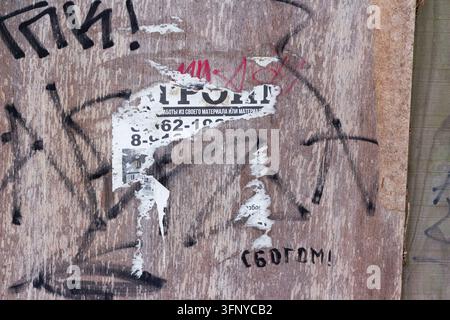 Verwitterter Holzzaun mit zerrissenen Werbefragmenten und handgeschriebenem kyrillischem Graffiti mit der Aufschrift ‚mit Gott‘, urbane Verfallstextur: Russland - 28. Januar 20 Stockfoto