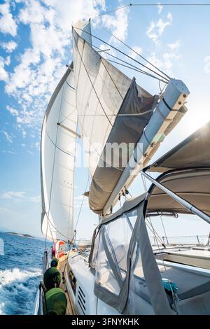 Blick vom Deck eines Segelboots mit vollständig aufgezogenen Segeln, das unter einem strahlend blauen Himmel über die Adria kreuzt. Dynamische maritime ReiseSzene Stockfoto