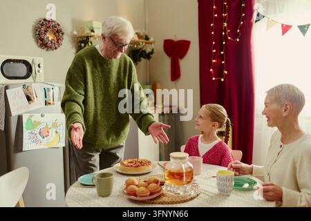 Senior-Großeltern mit Enkeltochter, die zu Hause einen festlichen Tee genießen Stockfoto