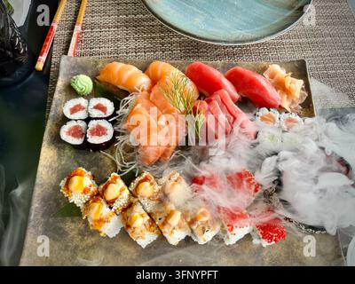 Premium-Sushi-Sashimi-Platte mit dramatischem Raucheffekt Stockfoto