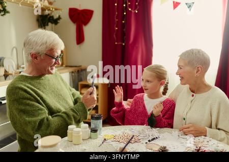 Seniorenpaar und Mädchen haben einen Videoanruf während des Weihnachtsbastelns Stockfoto