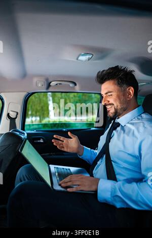 Geschäftsmann führt Videokonferenz über Laptop im Auto Stockfoto