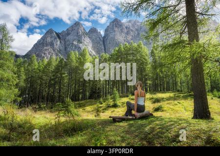 Wanderin sitzt auf einer Holzbank im Herbstwald in Slowenien Stockfoto