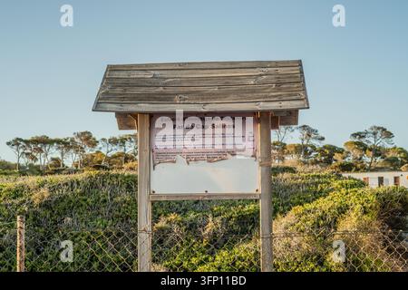 Ein hölzernes Informationsschild im Freien beschreibt die 'Estació d'Investigació Costanera Far de Cap Salines' auf Mallorca, Spanien. Das Schild, verwittert und Stockfoto