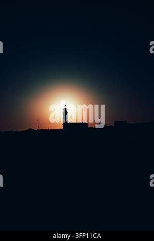 Eine auffällige Silhouette des Leuchtturms von Cap de Formentor, gelegen auf Mallorca, Spanien, hebt sich während der goldenen Stunde deutlich gegen die strahlende Sonne ab Stockfoto