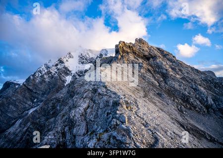 Der Ortler erhebt sich majestätisch in den italienischen Alpen am späten Nachmittag. Wolken ziehen darüber hinweg, und felsige Hänge schaffen eine dramatische Szene. Die schneebedeckten Gipfel reflektieren das Sonnenlicht. Stockfoto