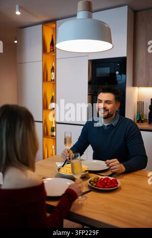 Paar genießt romantisches Abendessen mit Champagner in der heimischen Küche Stockfoto