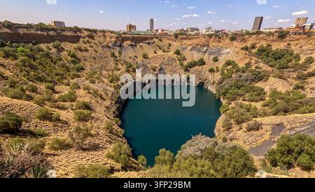 Luftbild der historischen Big-Hole-Diamantenmine, gefüllt mit tiefblauem Wasser, umgeben von arider Landschaft und der Stadt Skyline in Kimberley, Norden Stockfoto