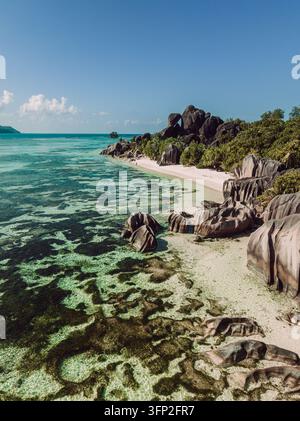 Vertikales Luftpanorama einer abgeschiedenen tropischen Küstenlinie mit Granitfelsen und türkisfarbenem Wasser auf La Digue. Stockfoto